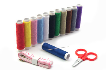 Colorful sewing thread rolls and needle on blue roll with sewing kits  isolated on white background.Full dept of field. Craft concept.