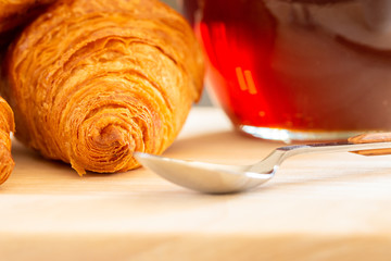 Close up and selective focus of Fresh croissants, spoon and honey jar over wooden board, breakfast, food background
