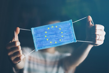 medical mask in hands of man, with the flag of  European Union painted. Copy space