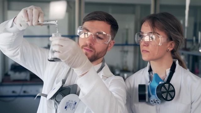 man and woman scientists in the lab are examining water and soil in a test tube