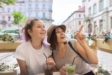 Two women in outdoor cafe talking, drinking summer ice cold drinks