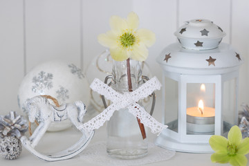 Weihnachtsdekoration in Weiß mit Christrose in Glasflasche und Laterne