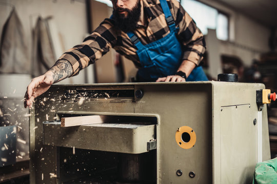 Focused professional carpenter working in his workshop, woodworking and craftsmanship concept.