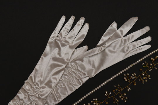 a pair of white silk gloves with pearl embellishment