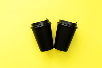 Two disposable coffee cup on yellow.