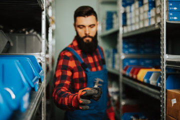 Handsome adult man working in car and truck spare parts warehouse.