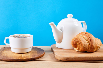 breakfast with croissants.Fresh crispy croissants and coffee on a blue background and wooden table