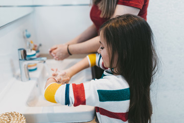 Coronavirus COVID-19 concept. Mother and daughter are washing their hands in bathroom with antibacterial soap.