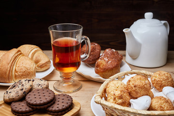 Hot tea put on table, drink breakfast in the morning day, breakfast with croissants and sweets on wooden table