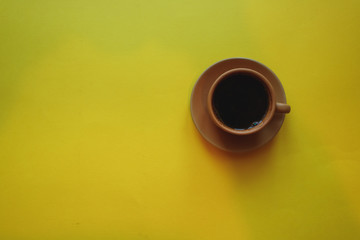 cup of coffee on yellow background with notepad