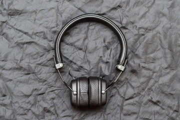 wireless bluetooth black headphones with leather ear pads on a black crumpled background