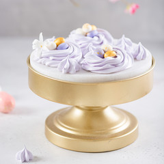 Easter bird nest meringue cookies - lilac mini Pavlova desserts with pastel candy eggs in nest shape for Easter holiday party. Side view, close up. Confectionery, bakery concept, greeting card, poster