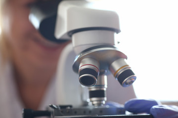 Woman look microscope on the background laboratory is a study human biology analyzes for non-compliance with the requirements organization public health at international level