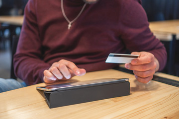 Shot of an unrecognizable man doing online shopping on his digital tablet and holding his credit card	