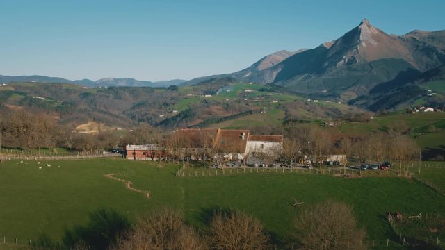4K Aerial Basque Country rural village in countryside, emblematic Txindoki mountain green fields and meadows
