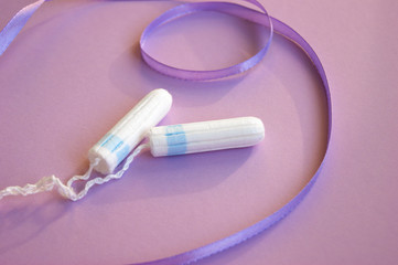 Menstrual pads and tampons on menstruation period calendar with on lilac background.