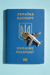 Ukrainian foreign passport with metal figure of small airplane on sunny light blue background. Conceptual trendy photo of travel and aviation