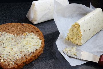 Homemade compound butter with bread and knife on black marble