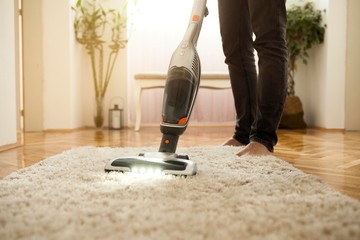  Man cleaning the carpet with vacuum cleaner in the living room