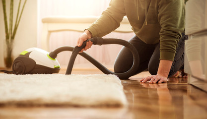  Man cleaning the carpet with vacuum cleaner in the living room