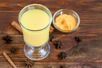 Masala tea or a traditional Indian drink with milk and spices, useful in winter to enhance immunity. On a wooden background.