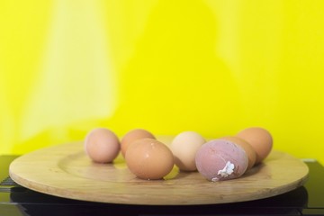 Boiled eggs on wooden plate, yellow background, copy space