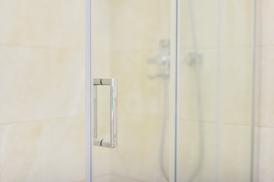 Shower, bathroom interior, light beige, glass door with chrome handle