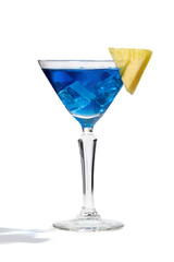 Blue Lagoon cocktail with ice cubes is contained in a martini glass with pineapple slice on the rim. The showy illustrative picture is made on the white background.