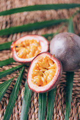 Yellow maracuya with palm leaves on rattan background. Copy space. Passion fruit. Creative design banner. Summer time. Tropical travel, exotic fruit. Vegan and vegetarian concept