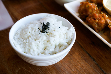 Rice in white cup on wood background and black sesame