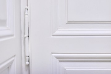 Antique white painted wooden door, vintage metal door hinge closeup