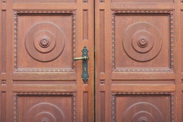 Detail of brown carved entrance double door, door handle close-up