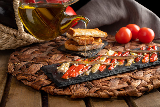 Escalivada washed down with virgin olive oil and vegetables in wicker basket on the rustic wooden table.