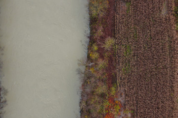 Aerial view of white murky river and fields next to it. Upside down photo of a river and fields in...