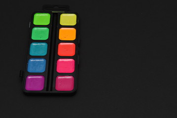 set of neon watercolor paints on a black background