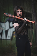 chica vestida de negro con el bate de The Walking Dead, en un descampado y diferentes poses para...