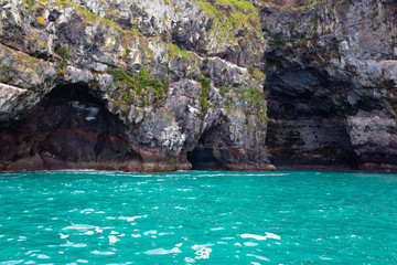 Cave in a cliff and turquoise water in a Akaroa, Banks Peninsula, South Island, New Zealand