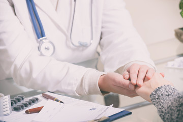 Woman doctor holding patient hand