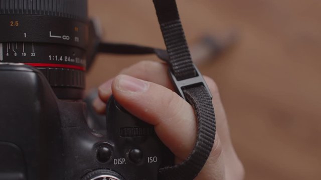 Top view of a part of the camera. A man's hand presses the shutter button on the camera and adjusts the focus. A man's finger presses the camera shutter