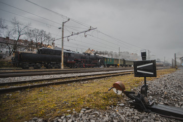 Old vintage steam train with black locomotive is running with low power on a railroad track in the...