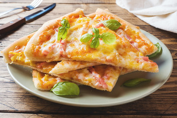 Pieces of homemade pizza on a plate on a wooden table.