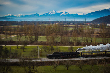 Old vintage steam train is running with loco reversed through the fields with magnificent...