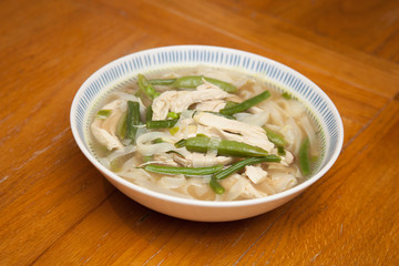 A bowl of Thai chicken soup with rice noodles and vegetables