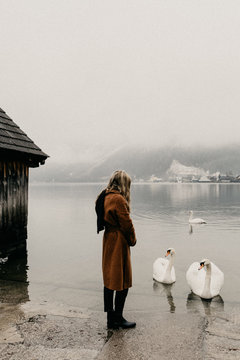 Young woman alone at a lake with swans