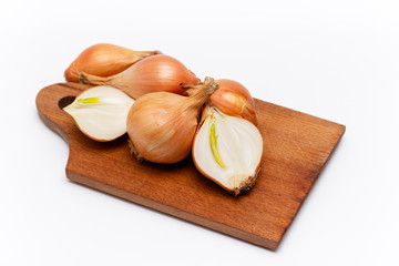 fresh bulbs of onion on a wooden cutting board on a white background