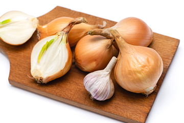 fresh bulbs of onion and garlic on a wooden cutting board on a white background