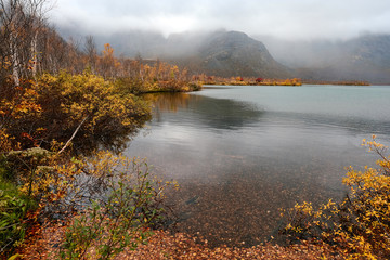 Autumn tundra on the background of cloudy misty mountains in rainy weather