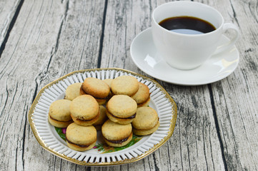 Traditional serbian vanilla cookies with jam, vanilice, on the plate, with cup of coffe in the background