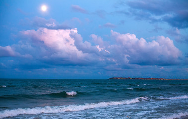 Fototapeta premium Sea coast on background of beautiful sky with clouds and moon, beautiful relaxing evening view