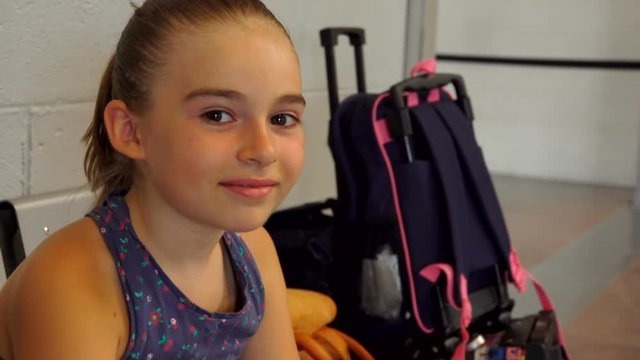 Adorable cute taned girl with big brown eyes is sitting in the airport lounge and smiling shyly
